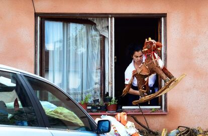 Una mujer saca un caballo de juguete por la ventana de su casa.
