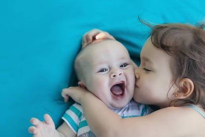 Una hermana mayor besa su hermano pequeño.