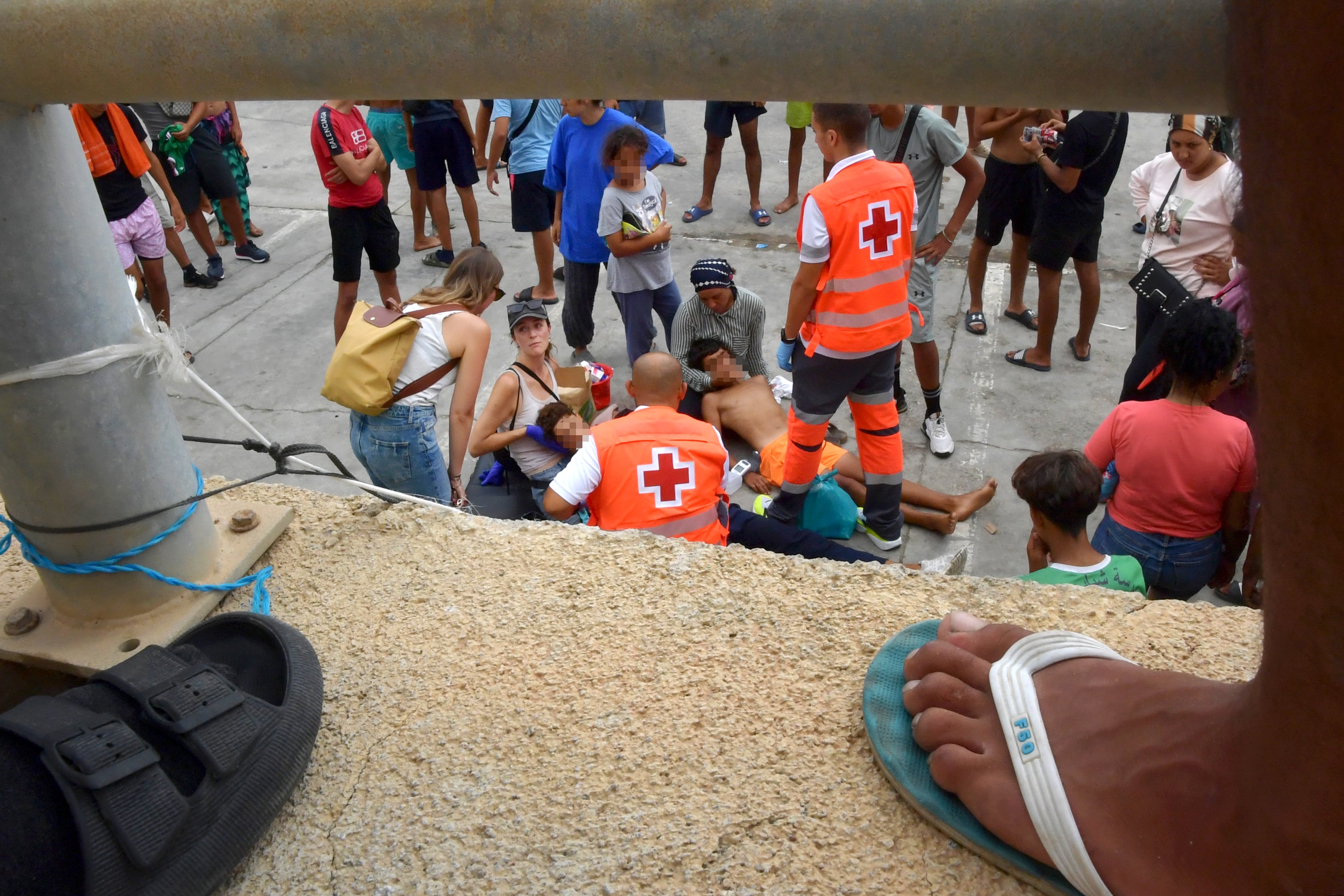 Dos migrantes desplomados en el suelo por la falta de comida y agua son atendidos por sanitarios.