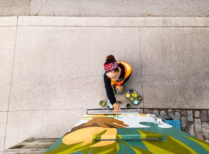 Joven artista latina pintando mural.