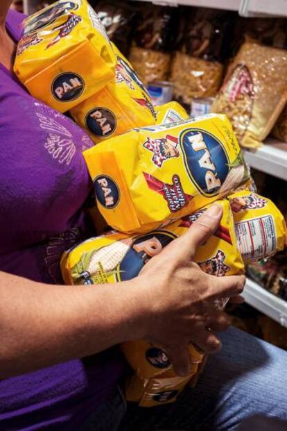 Mulher carrega pacotes de farinha para arepas, um dos produtos básicos em falta.