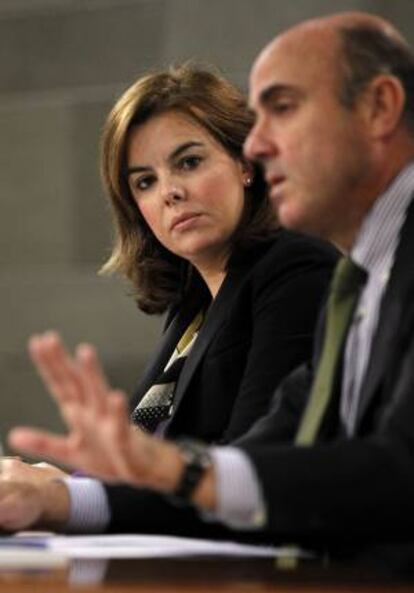 El ministro de Economía y Competitividad, Luis de Guindos, y la vicepresidenta del Gobierno, Soraya Sáenz de Santamaría, durante la rueda de prensa que han ofrecido hoy tras la reunión del Consejo de Ministros.