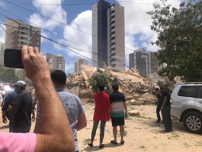 Pessoas observam os escombros de edifício residencial que desabou nesta terça-feira em Fortaleza. 