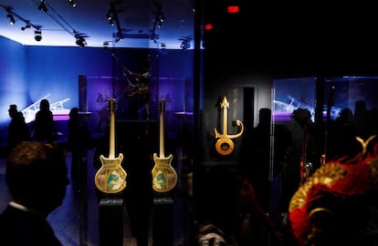 Varias personas observan las guitarras de Steve Miller (izquierda) y Prince (derecha), junto a un piano que tocó Lady Gaga (al fondo) durante la vista previa de la exposición 'Play It Loud: Instruments of Rock & Roll'.