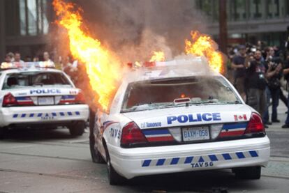 Un coche de policía en llamas en las calles de Toronto.