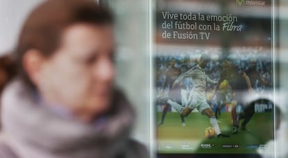 Una mujer pasa frente a un cartel de Movistar TV.