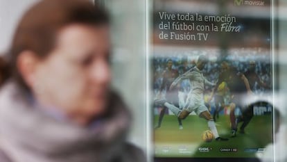 Una mujer pasa frente a un cartel de Movistar TV.