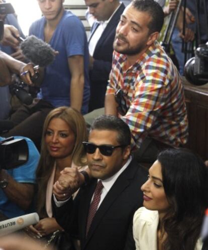 Os presos Mohamed Fahmy (centro) e Baher Mohamed (de pé, acima) falam com a imprensa ao lado da advogada Amal Clooney (direita) e da mulher de Fahmy.