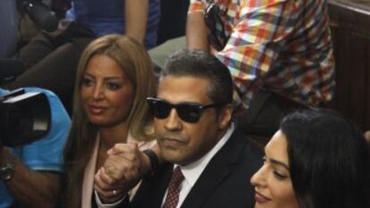 Os presos Mohamed Fahmy (centro) e Baher Mohamed (de pé, acima) falam com a imprensa ao lado da advogada Amal Clooney (direita) e da mulher de Fahmy.