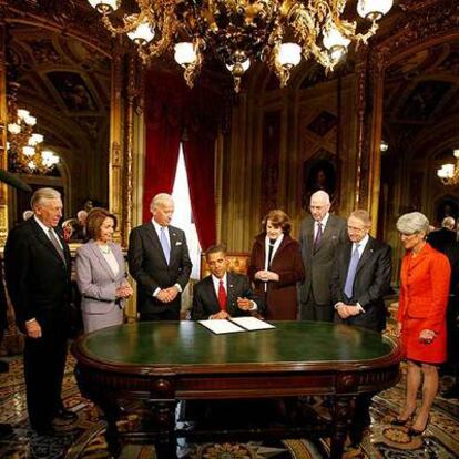 Obama firma uno de sus primeros documentos como presidente ante miembros del Congreso en el Capitolio.