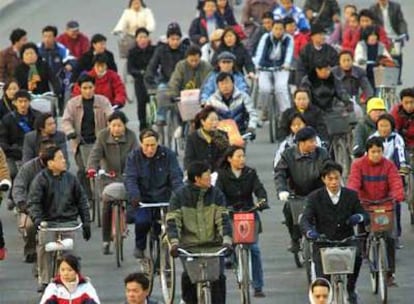Ciudadanos chinos circulando con sus bicicletas en una céntrica calle de Pekín.
