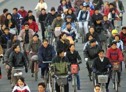 Ciudadanos chinos circulando con sus bicicletas en una céntrica calle de Pekín.