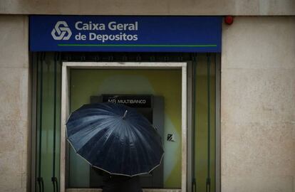 Un hombre saca dinero de un cajero de la Caixa Geral de Dep&oacute;sitos, en Lisboa.