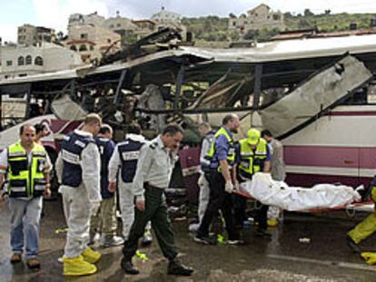 Policías y equipos sanitarios israelíes trasladan un cadáver del autobús que sufrió un atentado.