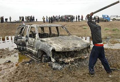 Un iraquí golpea con una barra, ayer por la mañana, uno de los dos coches en que viajaban los españoles atacados en Irak.