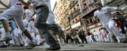 Los mozos, seguidos por los toros de Cebada Gago, toman la curva de la calle de la Estafeta durante el encierro de ayer.