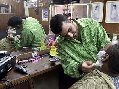 Un barbero iraquí afeita a un cliente en Kerbala, al sur de Bagdad, en 2002.