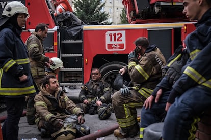 Los bomberos descansan tras trabajar en la extinción del fuego, este martes en el barrio de Gayrettepe (Estambul).