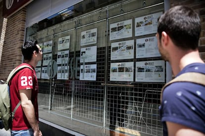 Dos jóvenes miran los anuncios de una oficina inmobiliaria en Madrid.