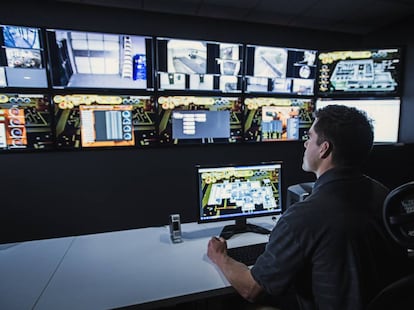 Un vigilante observa los monitores en una sala de seguridad. 