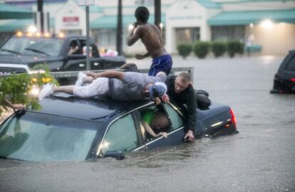 Mark Pickett, a la izquierda, y Ryan Craig, a la derecha, trabajan para rescatar a Bruce Salley, que quedó atrapado en su coche por las inundaciones en el estacionamiento de un supermercado en Rockford, Illinois (EEUU).