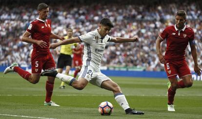 Asensio se dispone a golpear el bal&oacute;n ante Lenglet y Martins, del Sevilla.