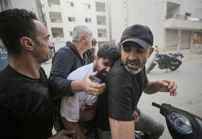 Varias personas trasladan a un herido en una motocicleta este viernes tras un ataque aéreo israelí en el barrio de Mreijeh en Beirut.  