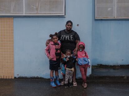 Priscila Santos con tres de sus hijas junto a un agujero de bala en el muro de una escuela del Complexo da Maré, en Río de Janeiro.