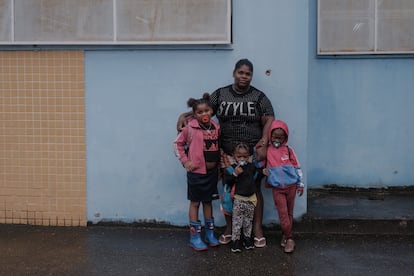 Priscila Santos con tres de sus hijas junto a un agujero de bala en el muro de una escuela del Complexo da Maré, en Río de Janeiro.