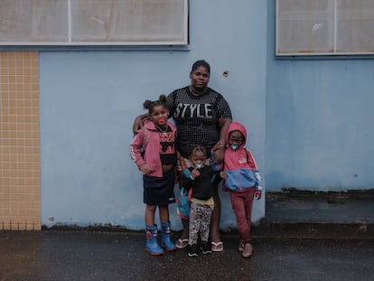 Priscila Santos con tres de sus hijas junto a un agujero de bala en el muro de una escuela del Complexo da Maré, en Río de Janeiro.