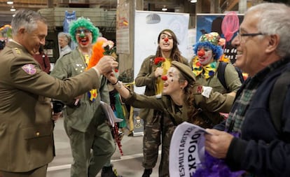 Una payasa le entrega una flor a un militar durante el acto de protesta pidiendo la desmilitarización de Expojove, la feria en Valencia destinada a niños y familias durante las vacaciones de Navidad.