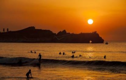 Surferos al atardecer en la playa de Salinas, en Castrillón (Asturias).