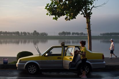 Una mujer china limpia un taxi cerca del Puente de la Amistad Sinocoreana, en la ciudad de Dandong, China.