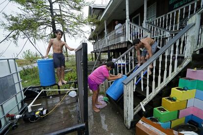 Habitantes de Luisiana mueven barriles de agua de lluvia que recolectaron de la tormenta tropical. Después del huracán 'Ida' no han tenido agua corriente.