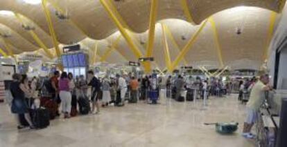 Decenas de pasajeros esperan con sus equipajes en la T4 del aeropuerto de Barajas, en el inicio de la primera operación salida de las vacaciones estivales. EFE/Archivo