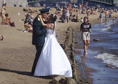 Una pareja de recién casados se besa ​​en una playa en el río Neva de San Petersburgo (Rusia).