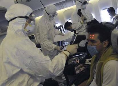 Sanitarios chinos examinan a los pasajeros de un vuelo procedente de México.