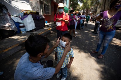 Un hombre le pone una mascarilla a su hijo mientras espera recibir comida de forma gratuita en Ciudad de México.