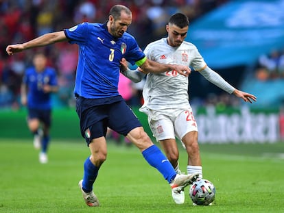 El defensa italiano Giorgio Chiellini (I)  disputa el balón con el mediocentro español Pedri (D) en las semifinales de la Eurocopa