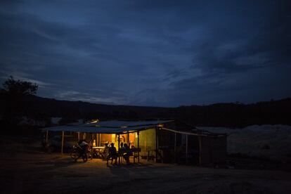 Los mineros de Areinha, se reúnen en el interior al atardecer alrededor de una mesa iluminada por un generador. 