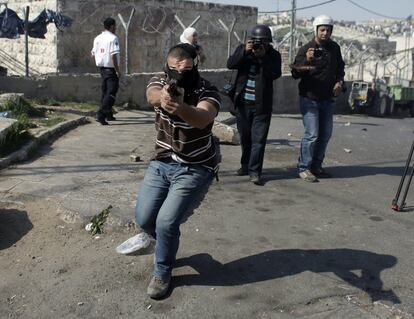 Un policía israelí apunta con su arma hacia los manifestantes y los fotógrafos palestinos durante los enfrentamientos en el barrio de Jerusalén oriental de Ras al-Amud, tras las oraciones del mediodía.