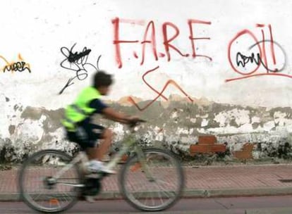 Un niño en bici pasa junto a unas pintadas racistas en Alcalá de Henares.