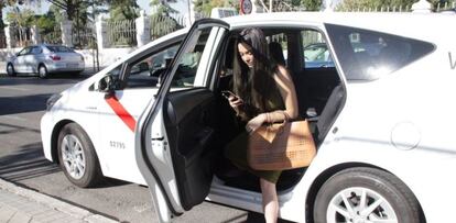 Una joven bajando de un taxi en Madrid contratado a trav&eacute;s de la aplicaci&oacute;n Cabify.