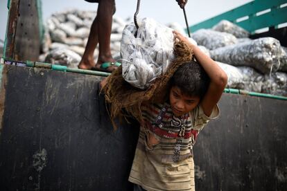 Asma Akter, de 10 años, carga bolsas de pescado congelado de un camión de mercancías en Nazirartek (Bangladés), el 23 de marzo de 2018.
