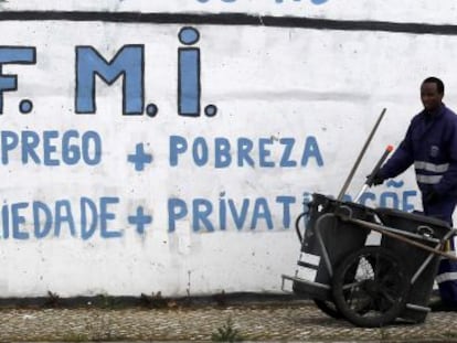 Un barrendero trabaja junto a una pintada crítica con el Fondo Monetario Internacional cerca de Lisboa. 