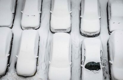 Coches cubiertos de nieve en un aparcamiento en Moscú (Rusia).