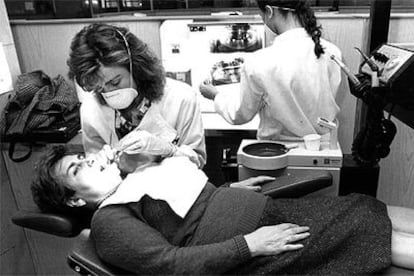 Una dentista examina la boca de una mujer.