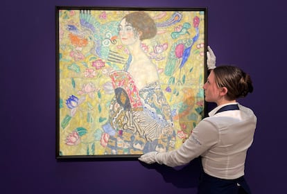 Una empleada posa con 'Dame mit Facher (Dama con un abanico)' del austriaco Gustav Klimt, durante una sesión fotográfica en la casa de subastas de Sotheby's, Londres, el 20 de junio de 2023.