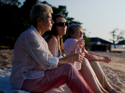 Three senior female friends enjoying leisure time on beach. Mature women friends discussing and laughing on sea coast. Relaxed retired women spending vacation together