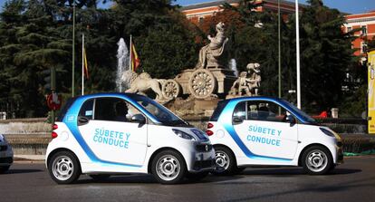 Coches de la empresa Car2go pasan por delante de la fuente de La Cibeles.